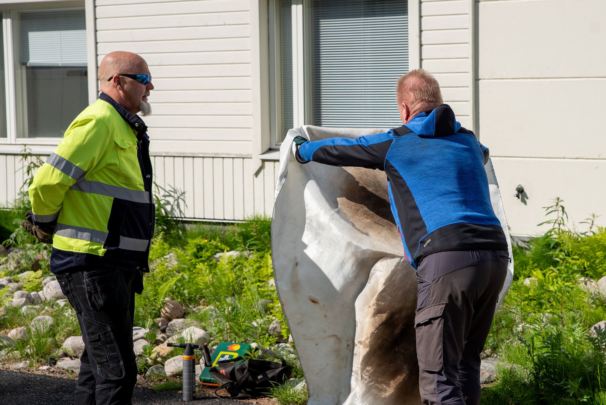 Henkilö käyttämässä sammutuspeitettä ohjaajan vieressä sammutusharjoituksissa.