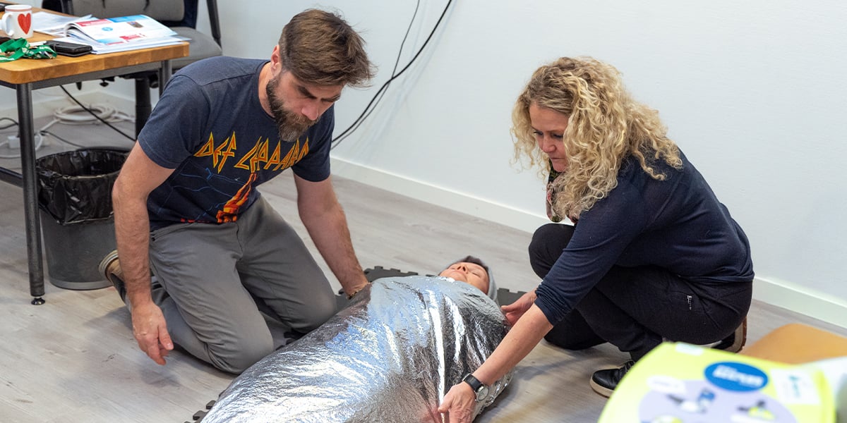 Kaksi ihmistä laittanut lämpösuojan ensiapuharjoituksissa ihmisen päälle.