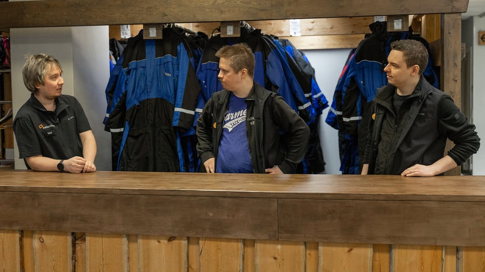 Kolme Safartican työtekijää haalareiden edessä juttelemassa.