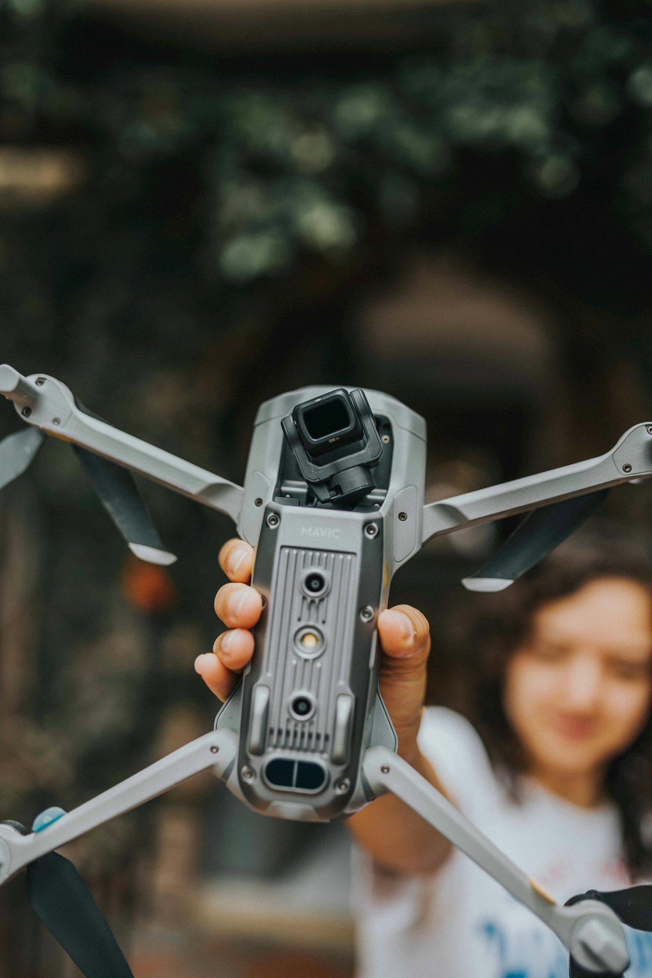 Ihminen pitää dronea kädessään osoittaen sitä kameraa kohti.