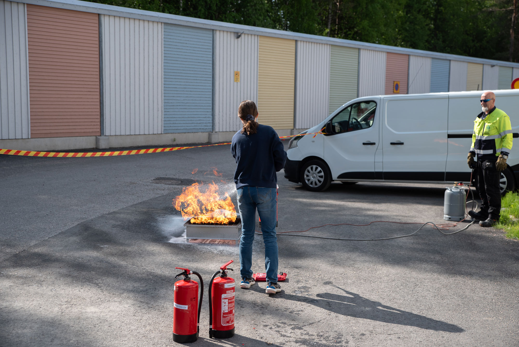 Henkilö alkusammutuskoulutuksessa harjoittelemassa sammuttimella tulen sammuttamista.